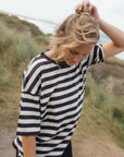 Woman wearing a black and white striped shirt outdoors with a natural background