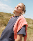 Person standing outdoors with a clear blue sky and grassy hill in the background