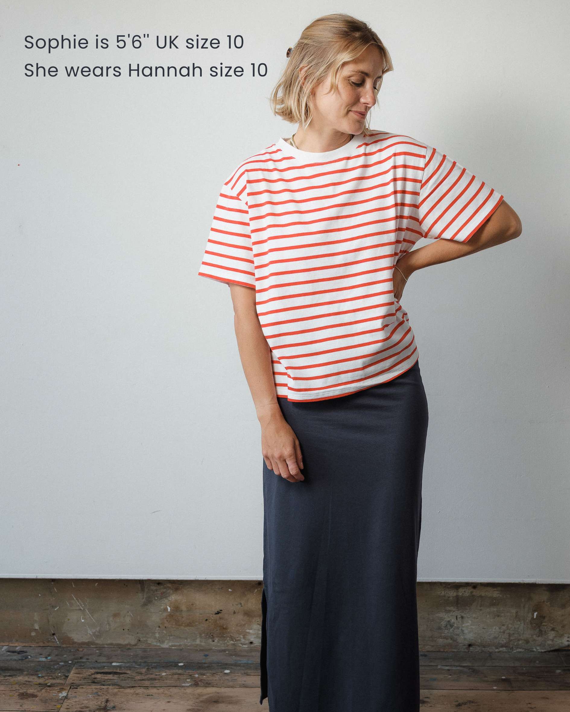 Woman wearing a red and white striped shirt and dark skirt against a plain background