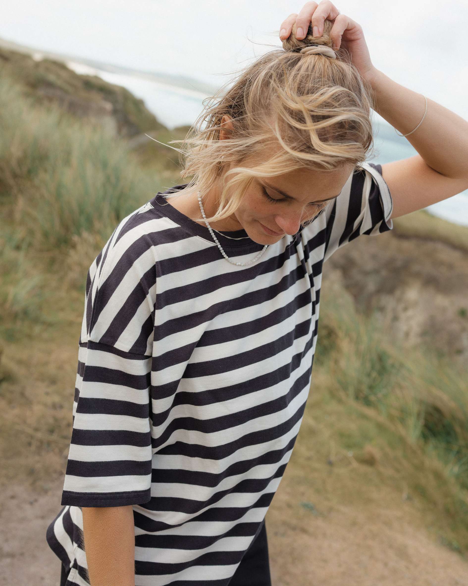 Woman wearing a black and white striped shirt outdoors with a natural background