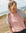 Woman wearing a pink shirt and grey sweatshirt on a beach