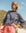Woman wearing a navy blue and white t-striped shirt with pink sweat shorts standing outdoors against a blue sky.