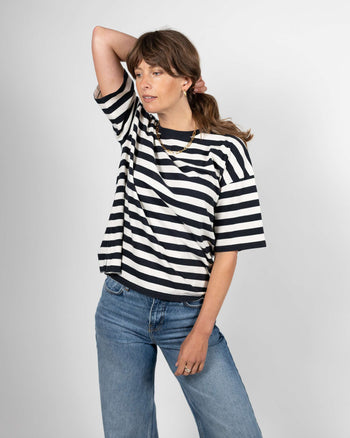 A person wearing a black and white striped t-shirt with elbow-length sleeves and a crew neck.